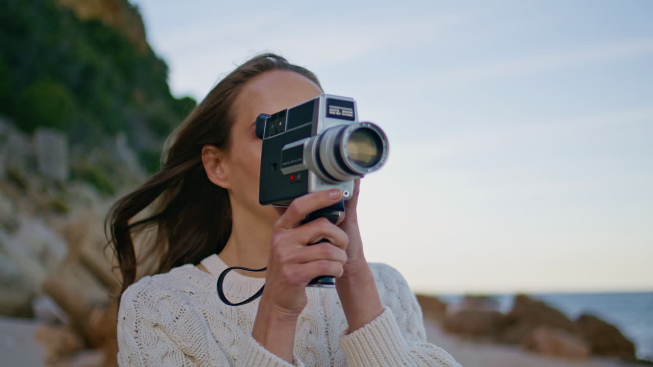 Tourist filming evening beach on vintage camera walking coast closeup