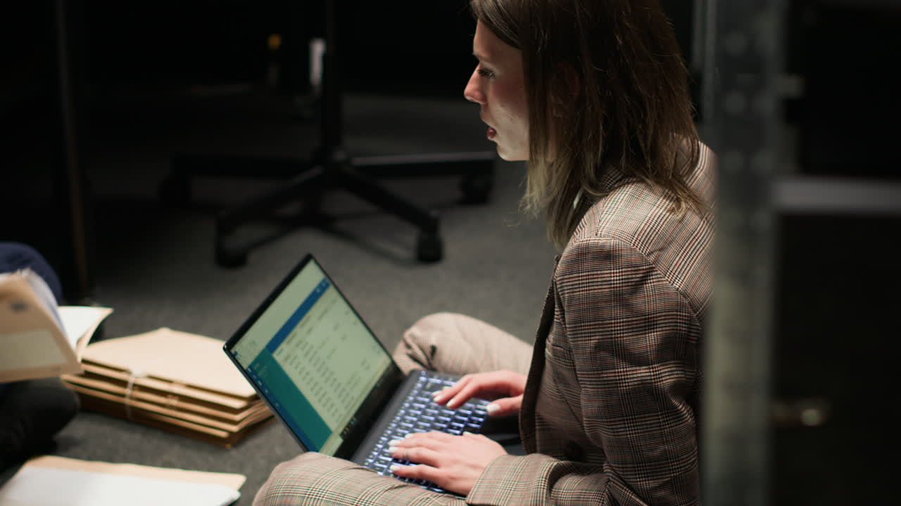 Woman working on laptop with files