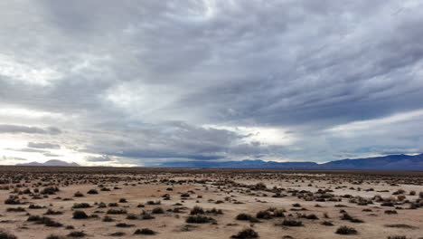 The-Mojave-Desert-basin-below-the-distant-mountain-range-on-an-overcast-day---sliding-aerial-flyover