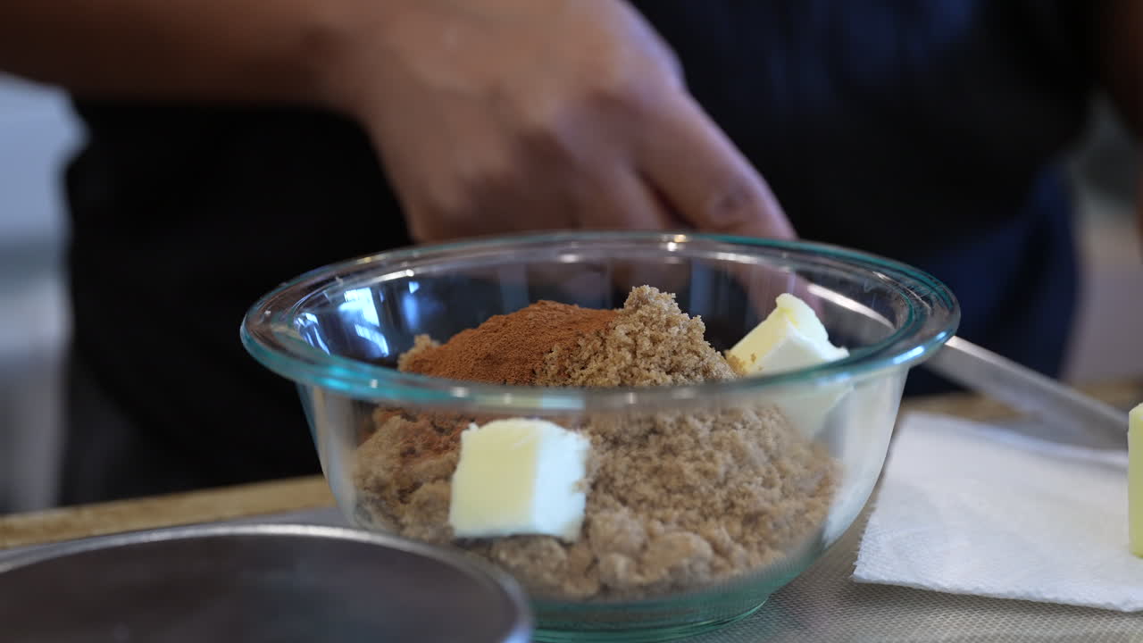 agregando mantequilla al azúcar moreno y canela para un delicioso relleno en un pastel - vista lateral en cámara lenta