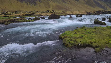 glacial river under volcanic hills on humid day in landscape of iceland