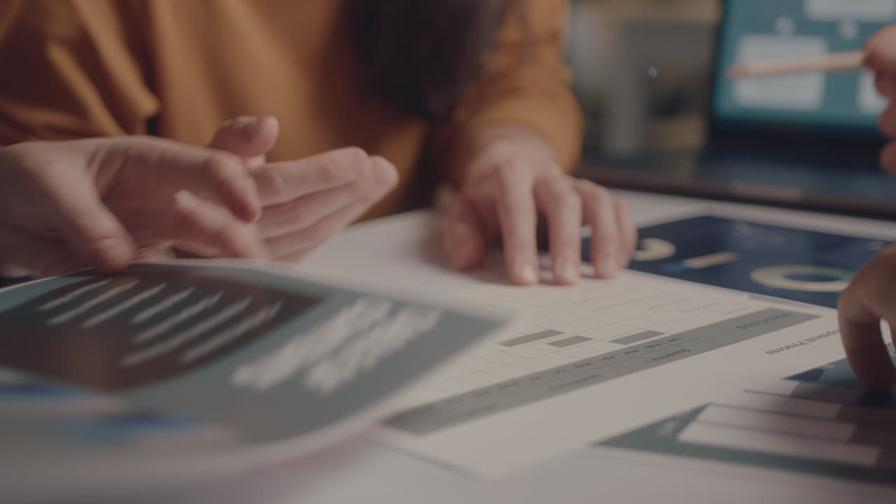 Hands of Colleagues Discussing Business Papers at Office Meeting