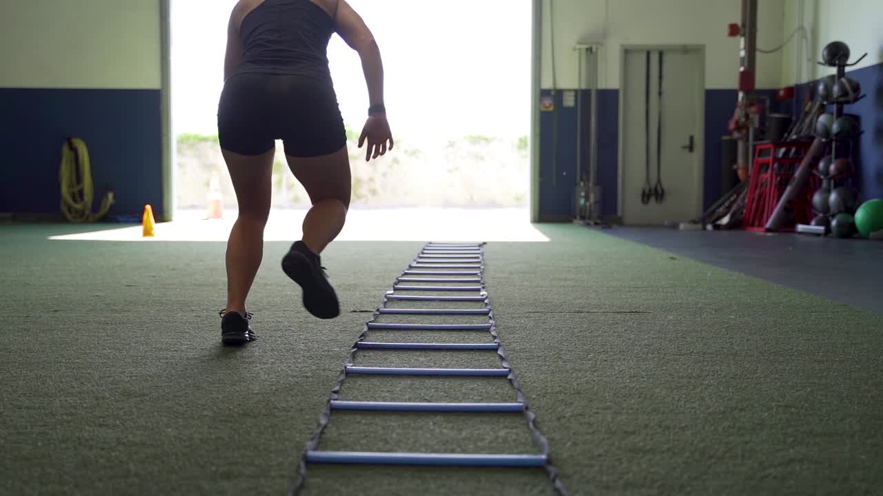 Female athlete using ladder to train in gym