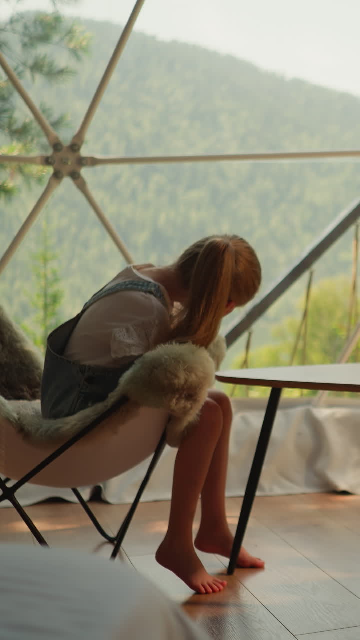 los hermanos se sientan en acogedoras sillas de lana en el campamento de glamping con vistas al bosque bajo el sol de la mañana. mañana en familia en un apartamento con vistas a las montañas. comodidad y tranquilidad