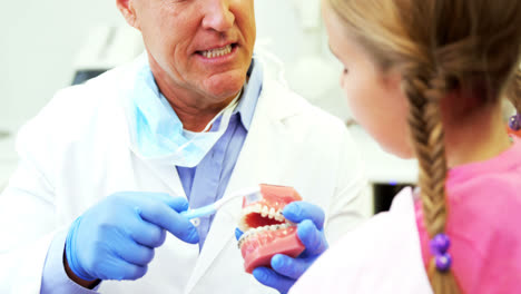 Dentist-showing-young-patient-how-to-brush-teeth