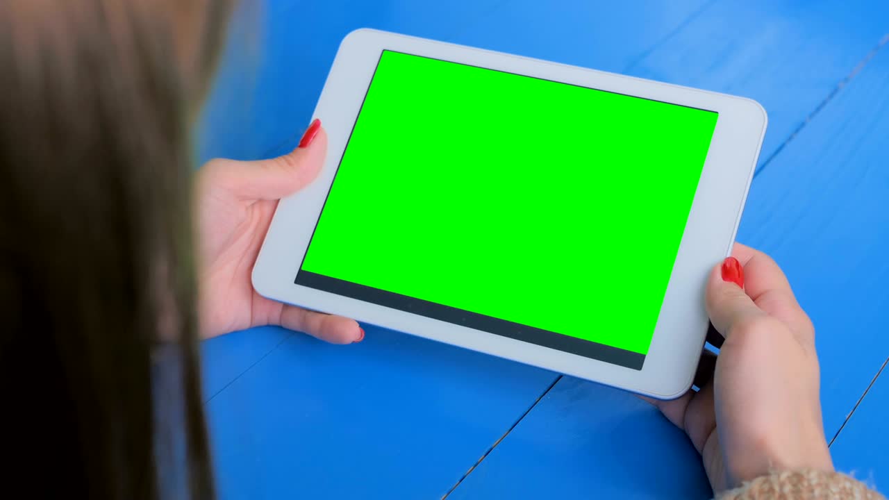 초록색 화면 을 가진 태블릿 컴퓨터 를 보고 있는 여자