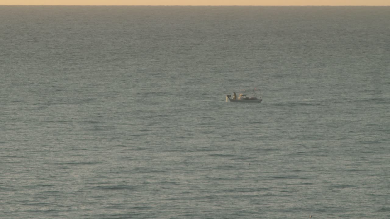Fisherman pulling in his catch onboard a fishing boat during golden hour