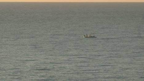 fisherman pulling in his catch onboard a fishing boat during golden hour