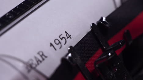 year 1954, typing on white paper in vintage typewriter, close up