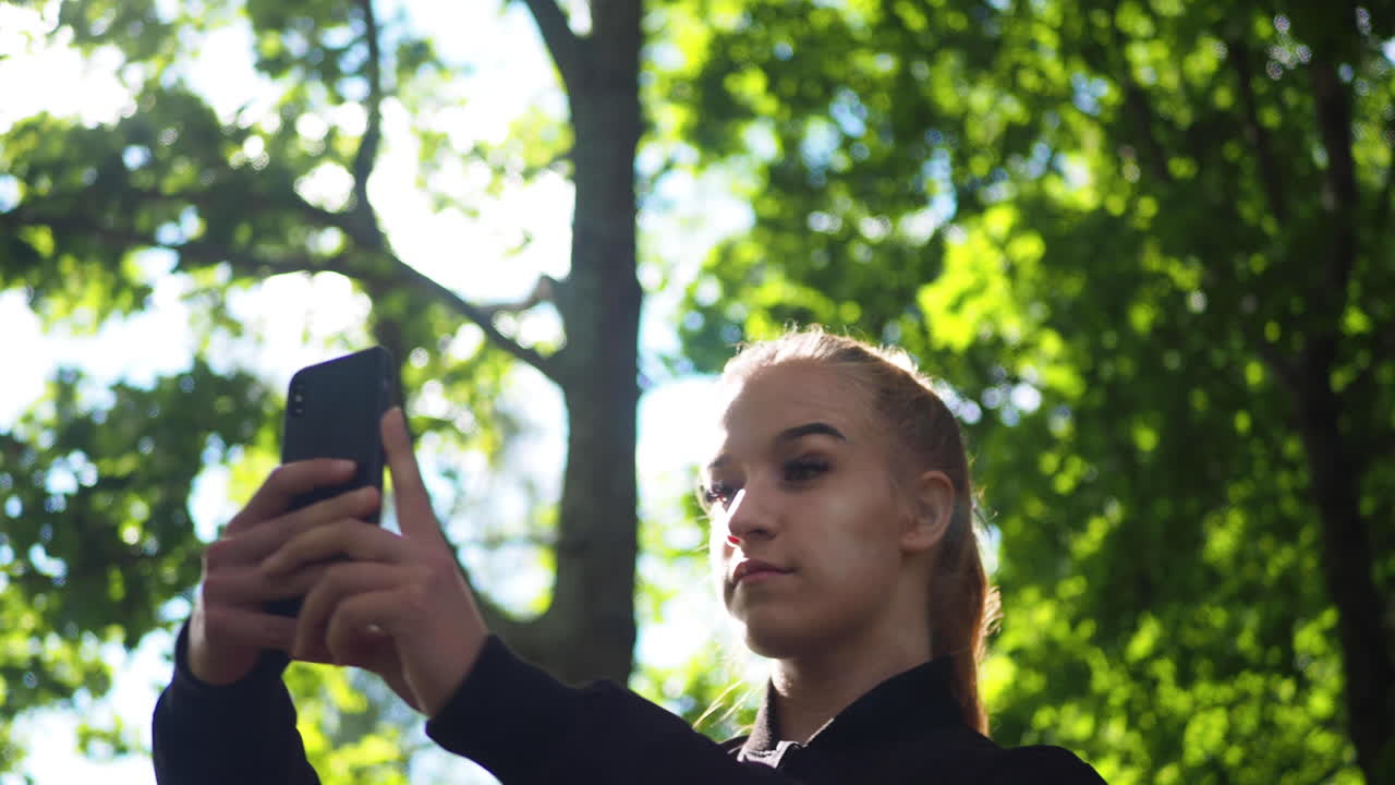 mujer joven tomando una foto selfie con un teléfono inteligente en el parque