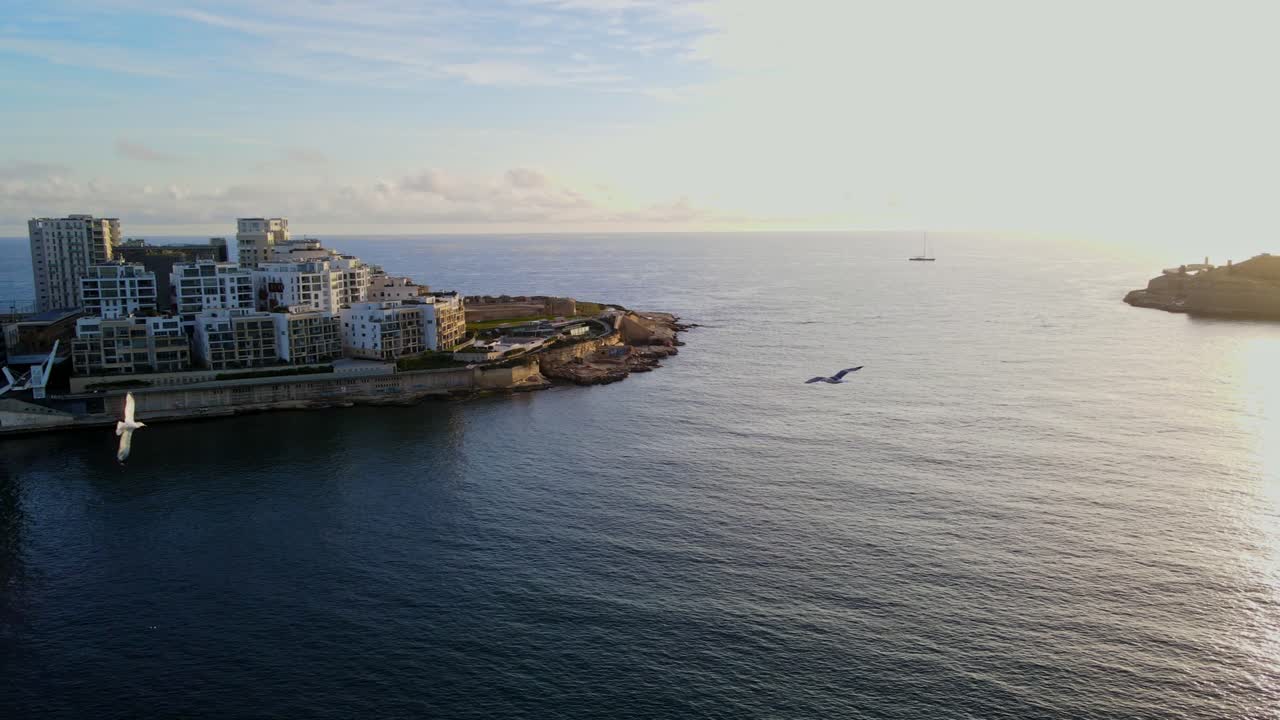 Vista aerea da drone della costa di Sliema con edifici moderni e il calmo Mar Mediterraneo a Malta