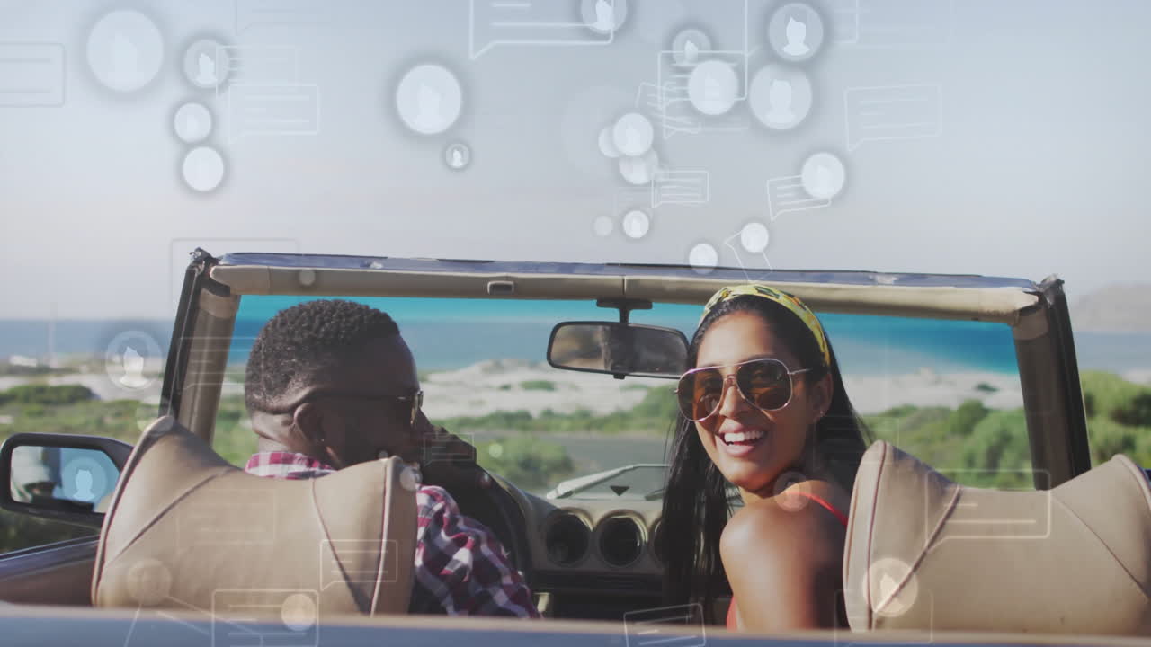 Driving convertible by beach, couple with animation of social media icons