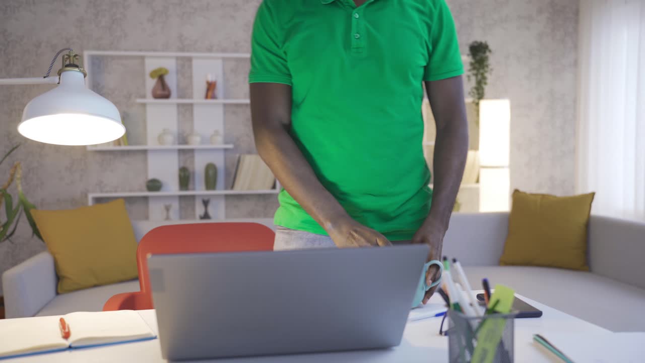 Giovane uomo africano allegro e felice che svolge il suo lavoro con piacere e passione nel suo ufficio domestico.