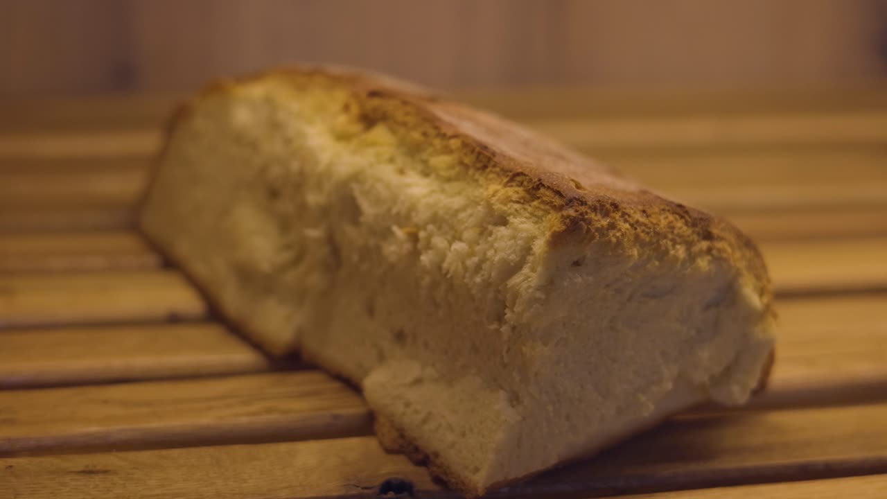 Loaf of baked bread with a thick golden crust on the shelf of the bakery, macro shot