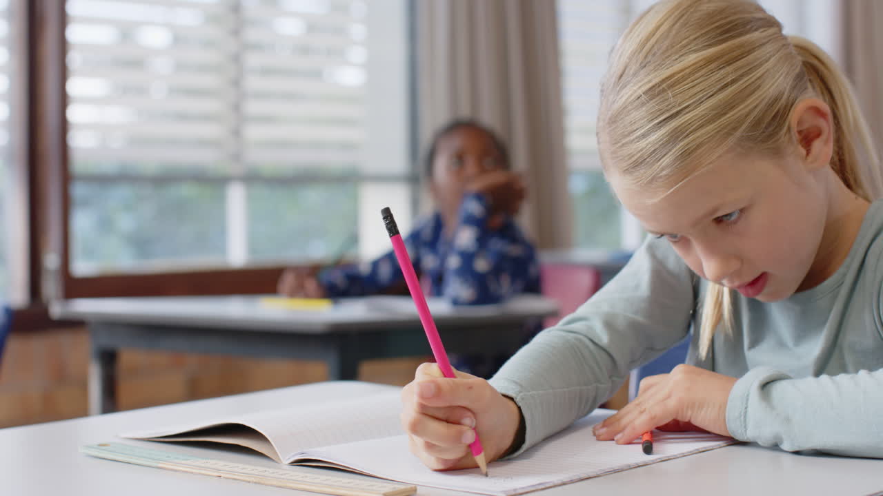 In school, girl writing in notebook at desk, concentrating on her work