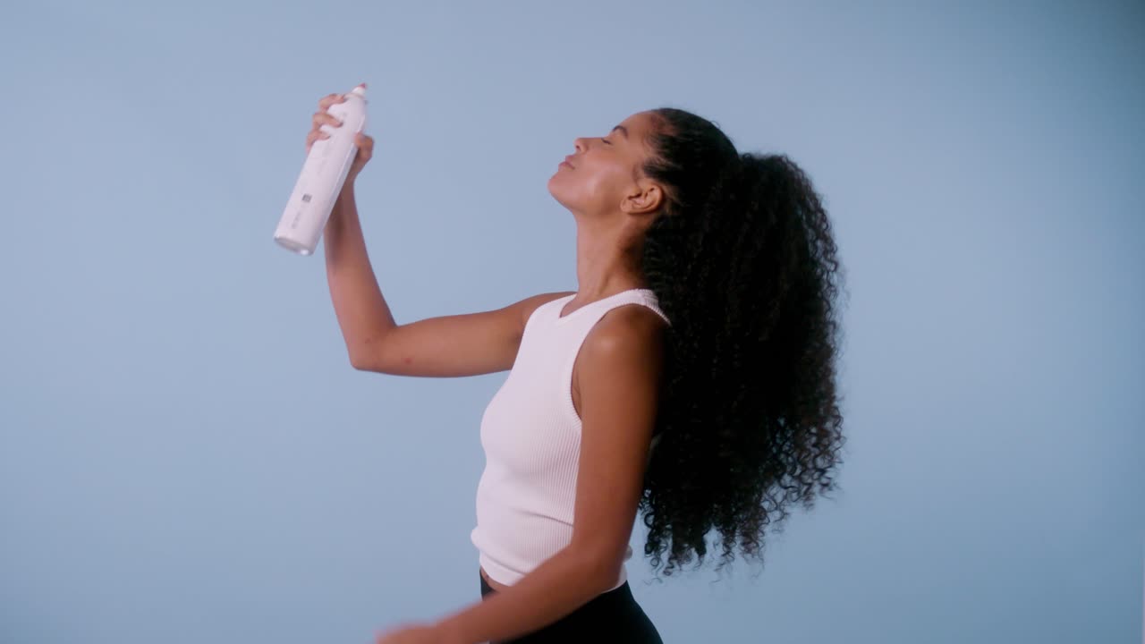 Model cheerfully displays a white spray bottle and applies it to her face, ending with a joyful smile at the camera