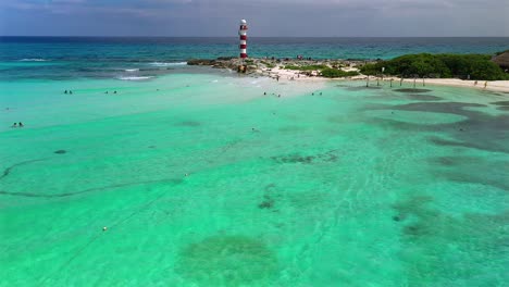 aerial drone footage over a blow up climbing structure, a kayaker, and people relaxing on a sandbar, in the turquoise waters, along the coast of the hyatt ziva in cancun mexico