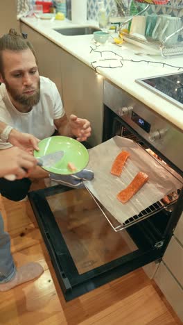 una pareja cocinando salmón en la cocina.