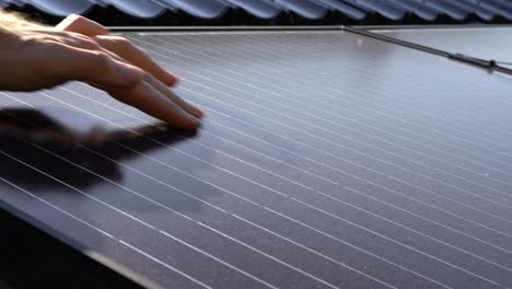 Close-up-of-hand-wiping-dust-off-solar-panel,-showing-dust-to-camera