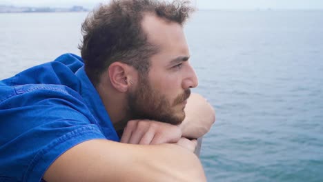 un joven pensativo mirando hacia el mar.