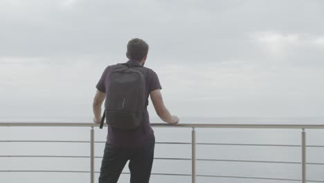 man with backpack looking at ocean view