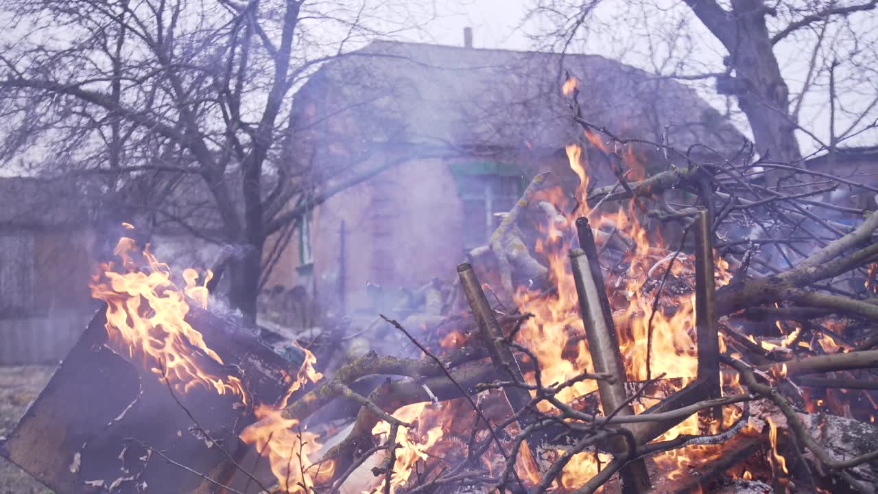 Burning garbage, branches, wooden furniture on fire in the backyard of a house in the village. Smoke from fire