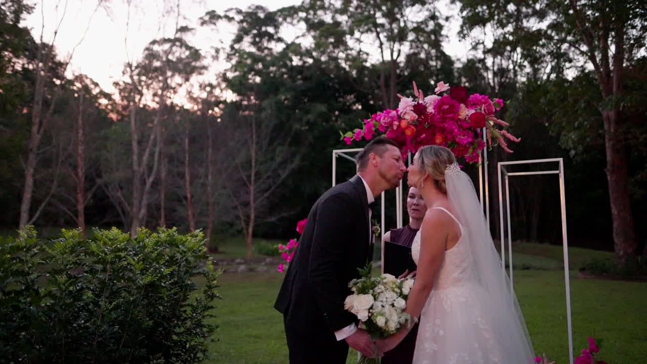 Bride And Groom Share I Do And First Kiss At Floral Altar During Outdoor Sunset Wedding Ceremony, 4K Slow Motion