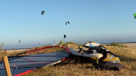 Langsamer-Schwenk-Nach-Links-Von-Surfsegeln-Und-Brettern-Im-Sand-Des-Strandes-Von-Tarifa,-Cadiz