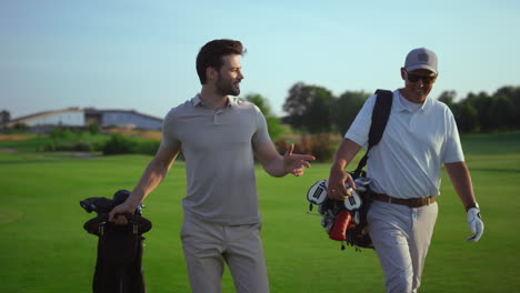Erfolgreiche-Golfspieler-Diskutieren-Lächelnd-über-Golf-Auf-Dem-Golfplatz.-Zwei-Männer-Genießen-Sportliche-Action.