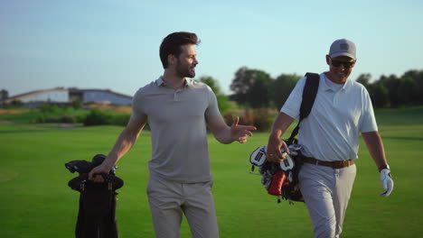 successful golfers smiling discuss golf on course. two men enjoy sport action.