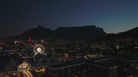 Aerial-descending-footage-of-city-in-evening.-Revealing-shopping-and-entertainment-centre-in-waterfront-borough.-Cape-Town,-South-Africa