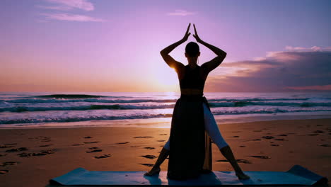 woman practicing yoga at sunrise on the beach