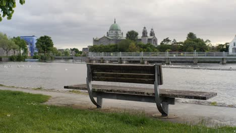Galway girl in grey jumpsuit walks past old bench along canal riverwalk in Ireland
