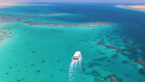 Luftaufnahme-Eines-Touristenboots,-Das-Anmutig-über-Das-Türkisfarbene-Wasser-Der-Blauen-Lagune-In-Dahab,-Ägypten-Gleitet-Und-Das-Konzept-Einer-Gemächlichen-Erkundung-Und-Ruhigen-Naturschönheit-Verkörpert