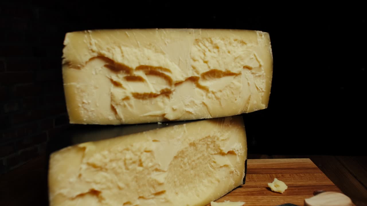 Medium hard cheese head parmesan on wooden board. Dolly-out shot