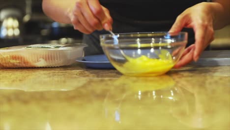 close up shot of a female mixing eggs in a bowl as part of preparing ingredients to start cooking