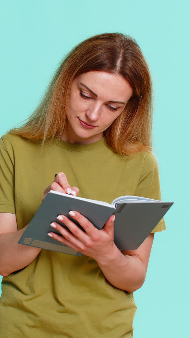 Woman writing in notebook then pausing thoughtfully looking up planning future or important decision