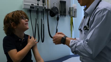 side view of young asian male doctor applying band aid on caucasian boy patient arm in clinic 4k