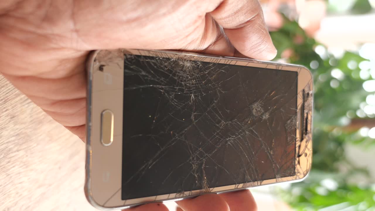 Broken phone with cracked screen held in hand