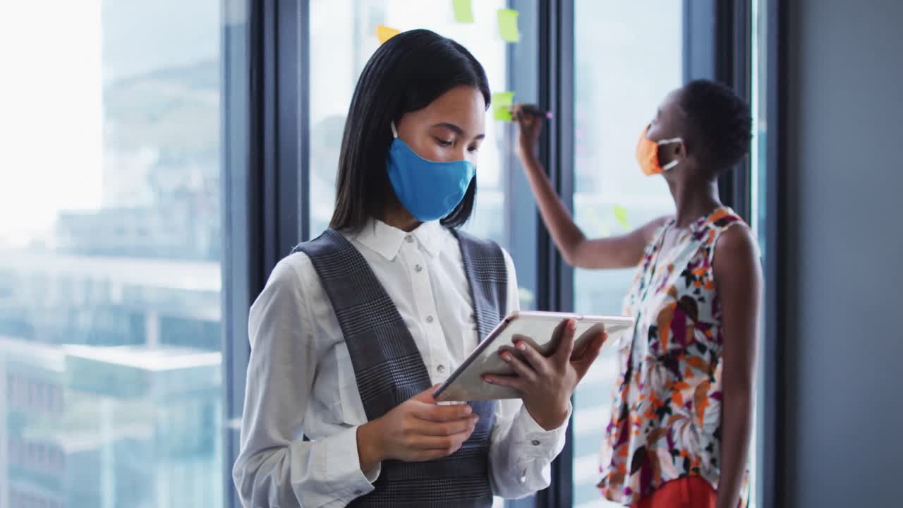 현대 사무실에서 디지털 태블릿을 사용하여 얼굴 마스크를 착용 한 아시아 여성의 초상화
