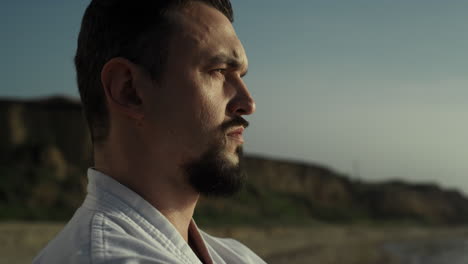 un luchador atlético de perfil mirando el atardecer, un deportista disfrutando de la naturaleza de la playa.