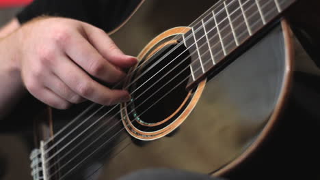 Man-finger-picking-black-acoustic-guitar-close-up