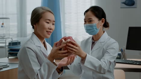 two medical professionals examine an anatomical heart model in a medical setting