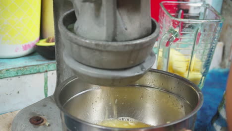 primer plano de una mujer que usa un exprimidor de metal para hacer jugo de limones para un batido de frutas en punta banco, costa rica
