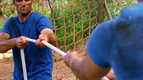 Couple-playing-tug-of-war-at-boot-camp