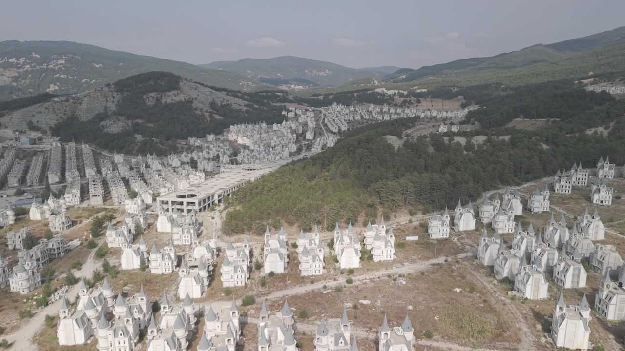 Türkiye'deki Burj Al Babas hayalet şehrinde, terk edilmiş Disney tarzı kalelerin sıraları arasında ileri doğru uçan 4K 10-bit sinematik drone çekimi.
