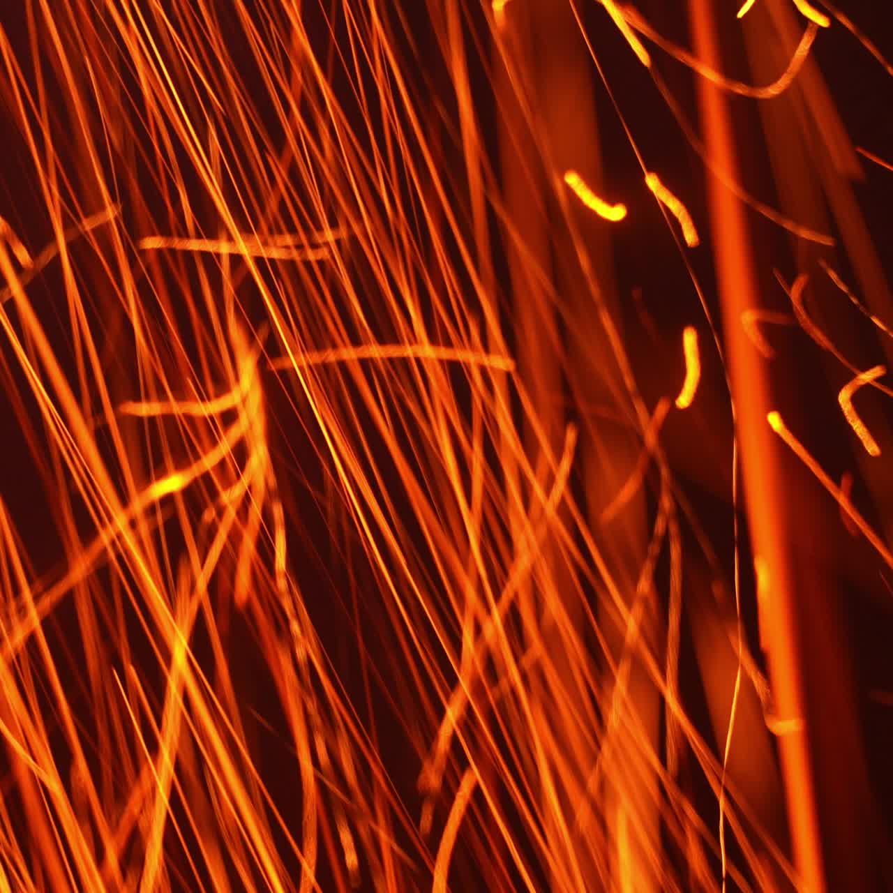Quick orange scintilla flying vertically down. Hot particles at a fast speed at black background. Close up