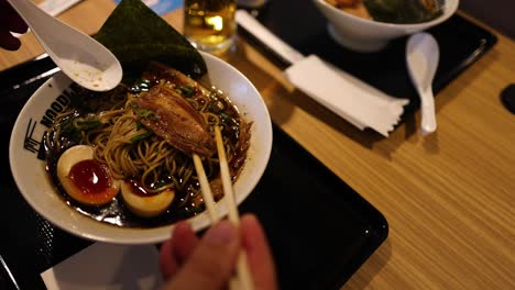 person eating ramen with chopsticks at a table