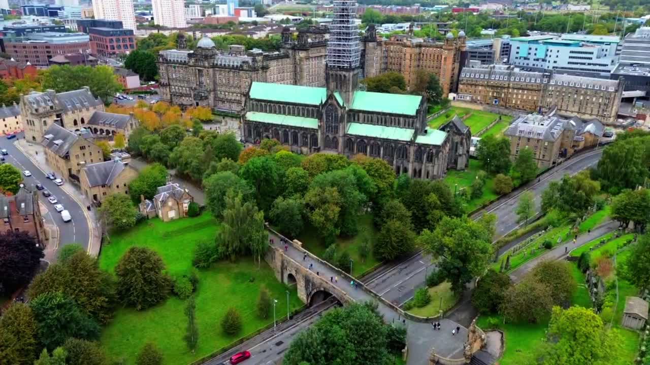 Glasgow Cathedral and the historic Necropolis area in Glasgow, Scotland, showing surrounding architecture, greenery, and urban landscape, aerial view