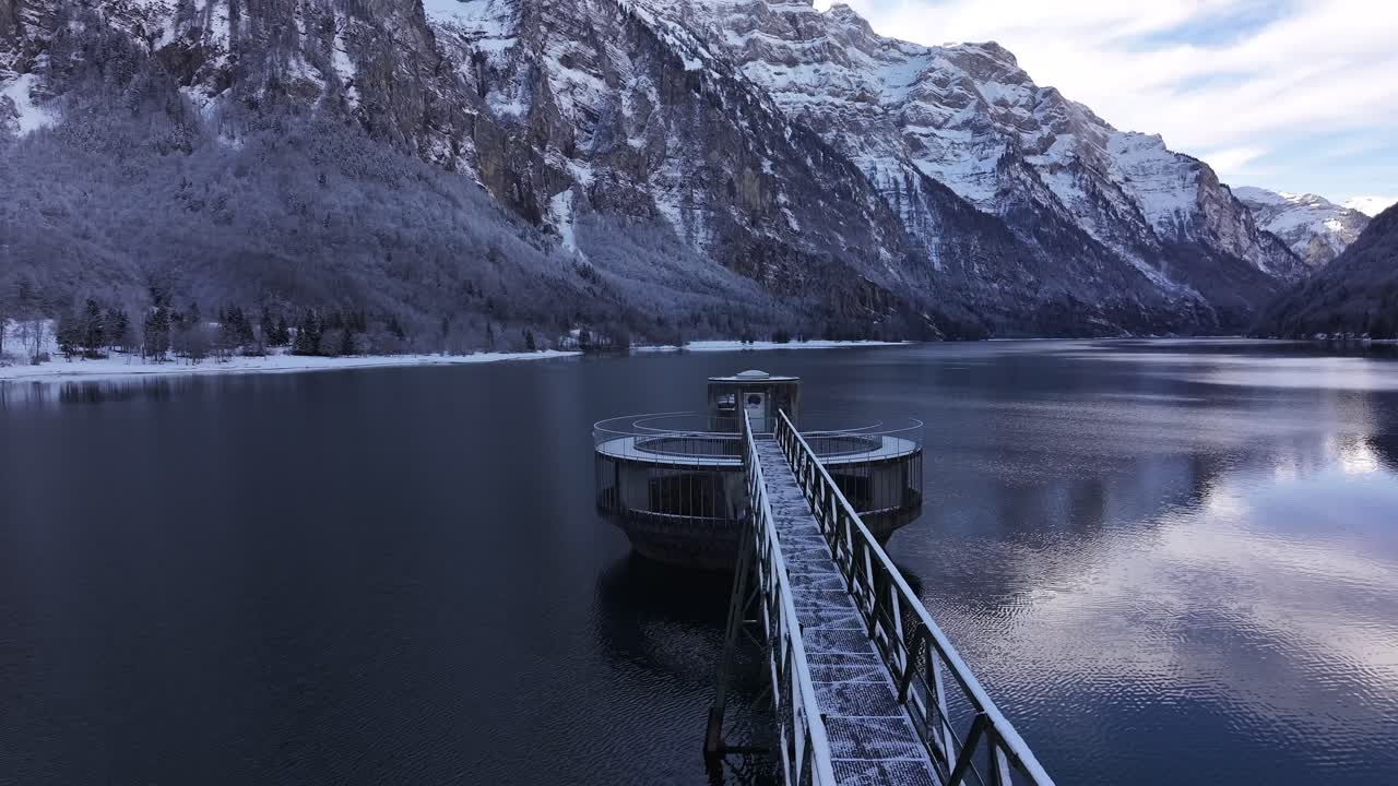 드론은 뒤로 당기고, klöntalsee, glarus, 스위스, 원형 물 흡수 구조, 조용한 반사 물과 눈 인 봉우리.
